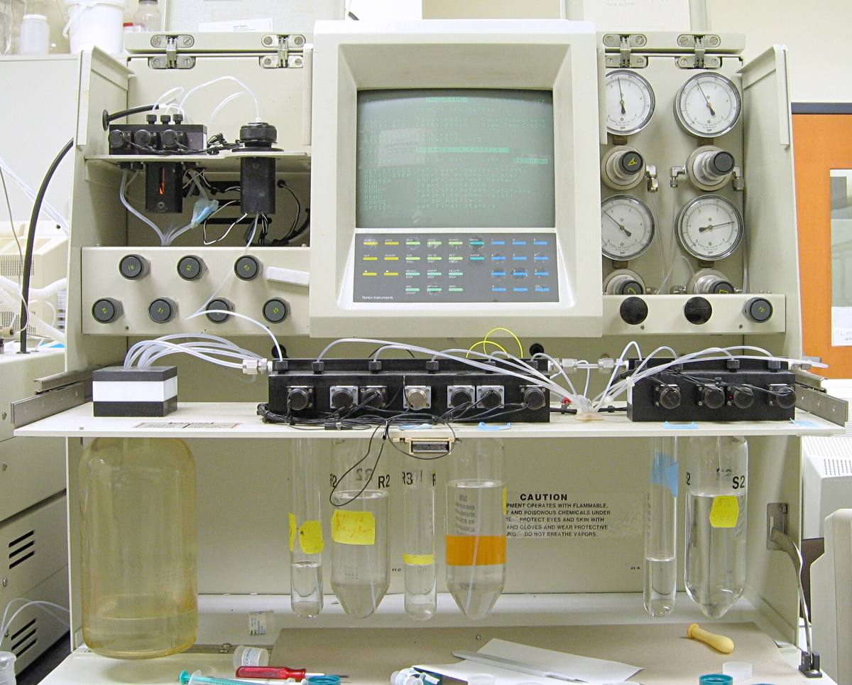 Laboratorní sekvenátor bílkovin s monitorem, tlakoměry a lahvemi s činidly