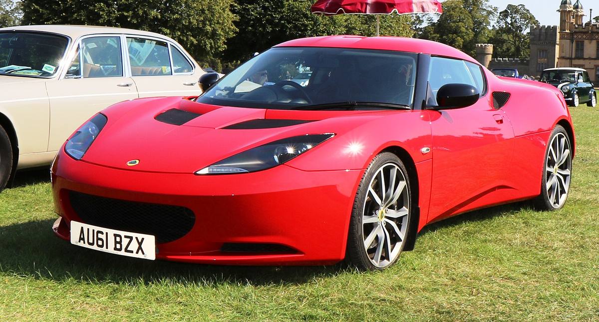 Červený Lotus Evora S na trávníku, zepředu z levého boku