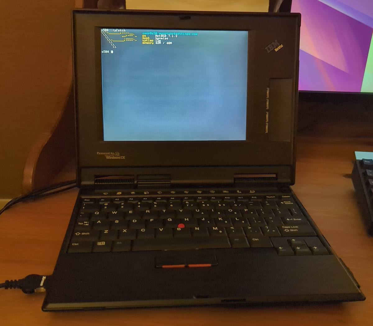 Otevřený kapesní počítač IBM WorkPad z50 na stole, na displeji terminál s výpisem NetBSD