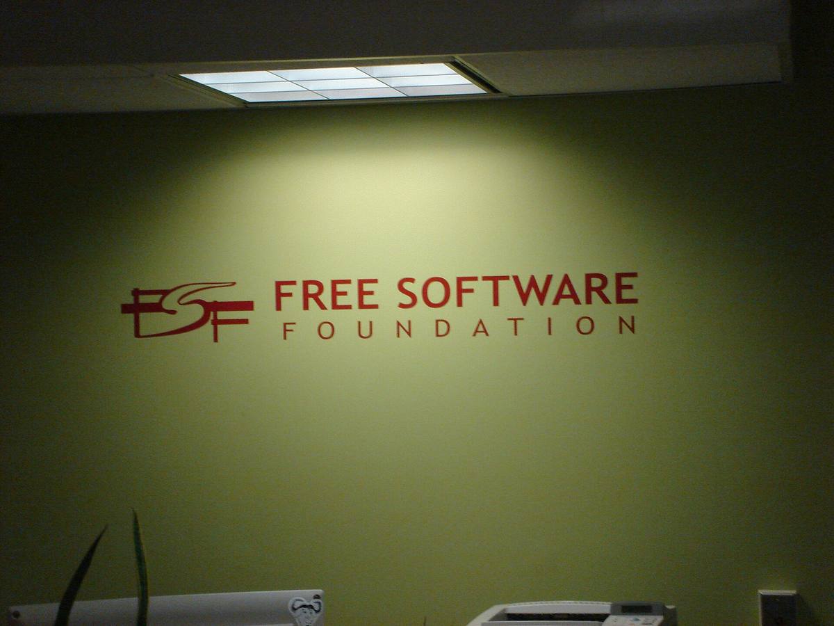 Červené logo Free Software Foundation na světle zelené stěně kanceláře